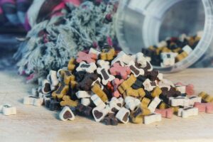 Umgekippte Box mit bunten Hundeleckerlis in Herz und Knochenform